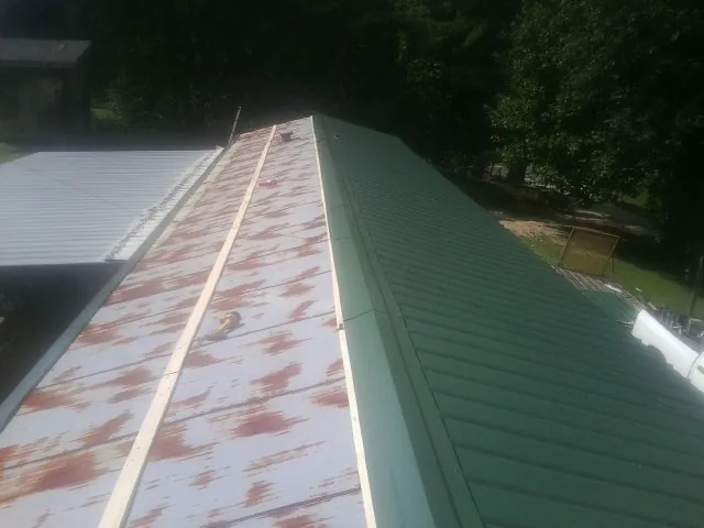 Old rusted panels beside newly installed green metal roofing — Wind Damage Roof Repair by Roofing Brothers in Cosby