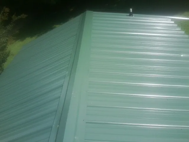 New green metal panels meeting at the ridge of a roof — Flat Roof Repair work by our crew in Cosby