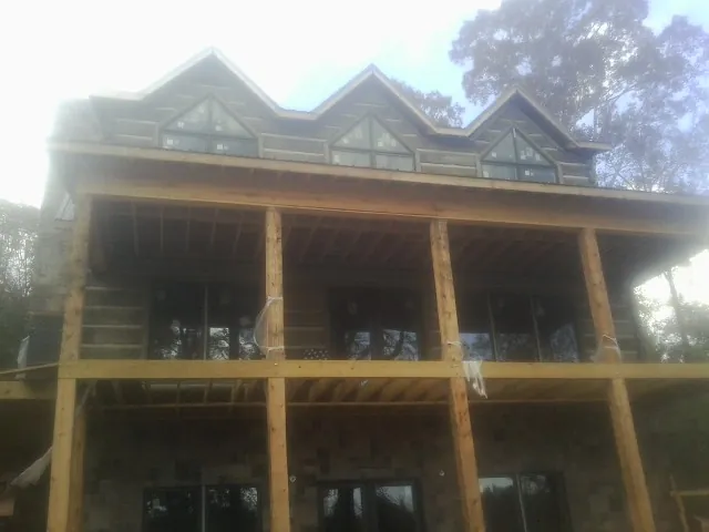 Dormers and porch framing on a large log home under construction — Roof Coating work by our crew in Cosby