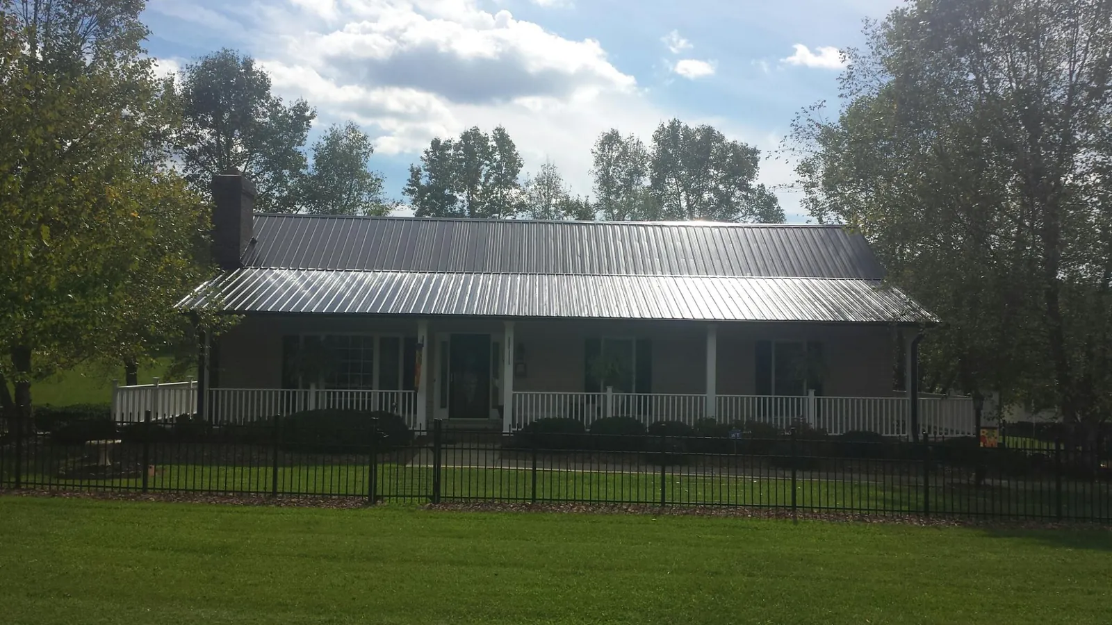 Gray metal roof on a brick ranch with a full width front porch — Gutter Guard Installation work by our crew in Cosby