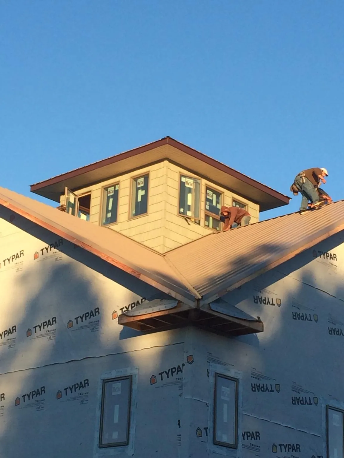 Roofers working around a rooftop cupola on a new metal roof at sunset — Roof Waterproofing in Cosby by Roofing Brothers